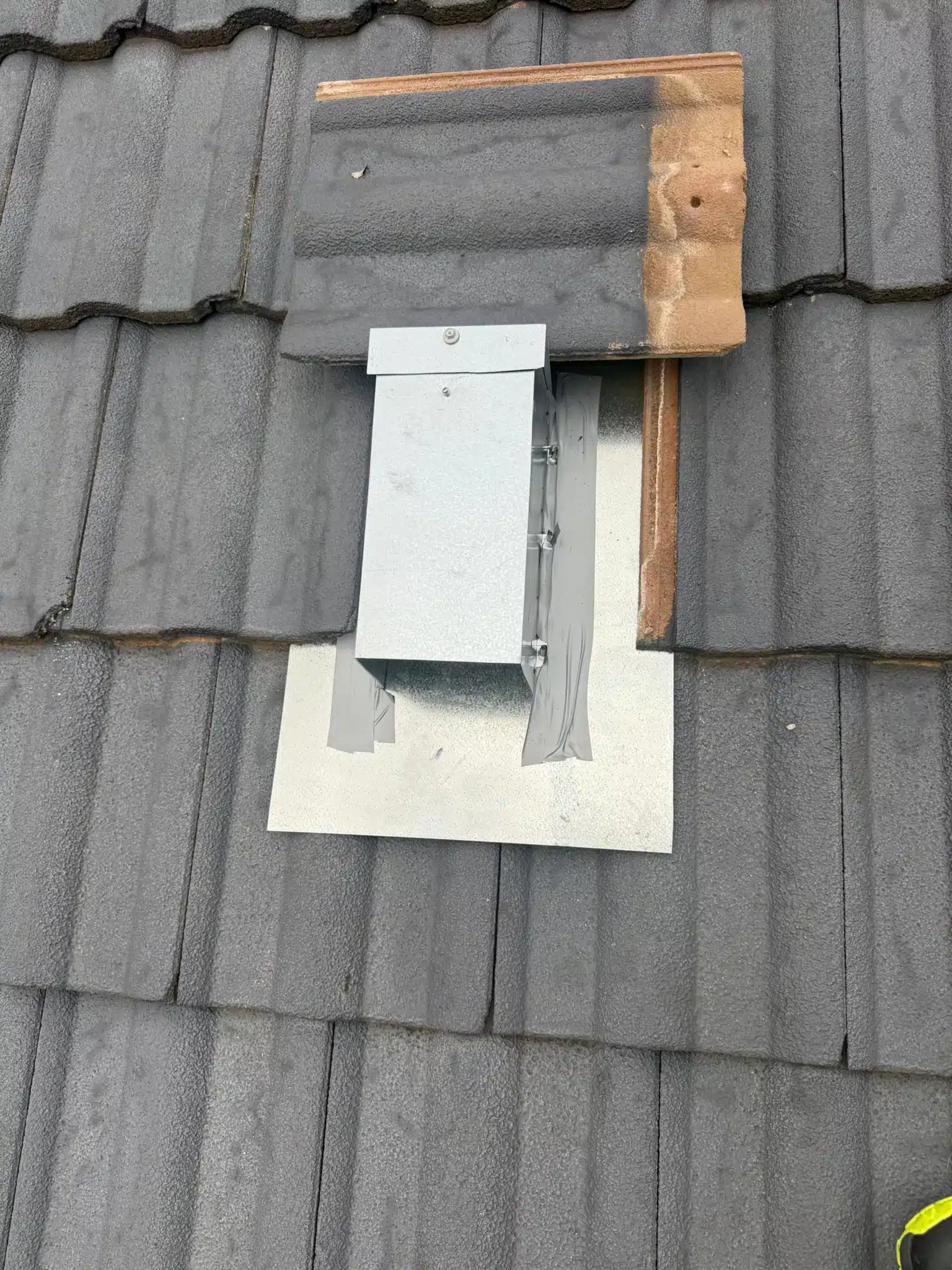 Custom galvanised one-way possum door installed on a tiled roof